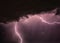 Flash of lightning in stormy night sky with clouds, natural phenomenon during thunderstorm