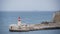 Flashing light lighthouse on the pier in the sea. Ship in the background, water, tourism, storm, nature, seascape