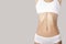 Flat belly and slender figure of a woman. Grey background. copycpase