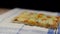 Flat bread pizza by cheese on a cutting board with flour on a napkin in black background slowly rotating.