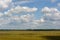 The flat and bright summer landscape. A shot against a blue sky with white clouds