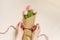 Flat female hands tie a satin ribbon bow on a simple bouquet of fresh pink tulip flowers in craft paper on a beige table