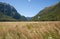 Flat grassed plains stretching in distance bordered by converging mountain ranges