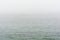 Flat grey sea with wavelets in the fog