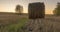 Flat hill meadow timelapse at the summer sunset time. Wild nature and rural haystacks on grass field. Sun rays and green