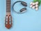 Flat lay of acoustic guitar, tulips bouquet.  white headphones on blue background with copy space. spring, love song and hobby