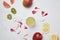 flat lay with alcohol cocktail, ice cubes, arranged exotic fruits and flower petals on white surface