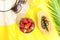 Flat Lay Arrangement of Hat Sunglasses Tall Glass with Fresh Tropical Fruit Juice Papaya Strawberries Palm Leaf on Yellow Backdrop