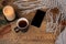 Flat lay background with mug of tea, black smart phone with blank screen, candles, knitted shawl with fringe, coniferous branches