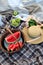 Flat-lay of basket with slices of watermelon, a bowl with green apples, a bouquet of pink roses, a straw hat, a top view.