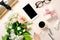 Flat lay beauty blogger workspace, top view feminine desk table with bouquet of rose flowers, smartphone, gift box, coffee cup,