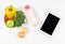 Flat lay of black blank screen computer tablet , vegetables and fruit in heart shape plate, bottle of wanter and two eggs. Healthy