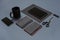 Flat lay of blank black paper sheet, black stationery items and coffee cup on gray desktop. Mock up