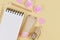 Flat lay with blank notebook and various cute items like rose flowers, cream tube in shape of cat, paper hearts and pencil