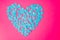 Flat lay of blue heart on bright pink background with copy space, top view. Valentine`s Day. Symbol of love