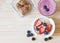 Flat lay of  breakfast with oat or granola in white bowl, fresh blueberries, strawberries, a  glass of blueberry smoothie and oat