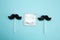 flat lay caramel on a stick in the shape of a mustache and a condom on a blue background