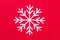Flat lay Christmas decoration of a white snowflake decorated on a red background