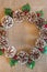 Flat lay Christmas wreath of pinecones, red berries, and holly leaves