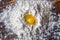 Flat lay, close up. A bright yellow quail egg yolk surrounded by a pile of white flour