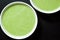 Flat lay. Close up. A round white plate filled with broccoli cream soup. Black background. Copy space