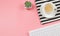 Flat lay of coffee cup on black and white stripes cloth with computer keyboard and cactus in plant pot  on pink background with