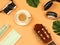 Flat lay of coffee cup, headphones ,camera,acoustic guitar,,medical face mask and alcohol sanitizer gel on orange background with
