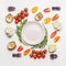 Flat lay of colorful salad vegetables ingredients around empty plate with seasoning on white background, top view.