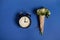 Flat lay composition of a beautiful bouquet of asters in craft paper and an alarm clock, lying on a blue background with space for