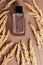 Flat lay composition bottle of man perfume with spikelets on brown background.