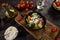 Flat lay composition of bowl of dumplings, jar of sour cream on wooden board