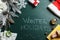 Flat lay composition of Christmas decorations, school items and alarm clock on blackboard with phrase Winter Holidays