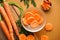 Flat lay composition with fresh carrots on a wooden kitchen board and carrots in small slices on a brown background