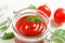 Flat lay composition with fresh tomatoes, basil and sauce in glass jar on white background, space for text