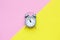 Flat lay composition of gray mini alarm clock. Copy space, pink and yellow background