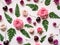 Flat lay composition of green fern leaves, cherries and roses of varying size and color on pink background