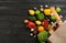 Flat lay composition with overturned paper bag and groceries on black wooden . Space for