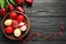 Flat lay composition of painted Easter eggs and flowers on wooden table, space for text