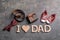 Flat lay composition with phrase I LOVE DAD small shoes and different gifts on grey background. Father`s day celebration