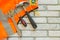 Flat lay composition with protective construction vest and working tool on brick wall background