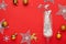 Flat lay composition with shiny confetti spilled out of champagne glass near Christmas decorations on red background, space for