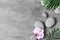 Flat lay composition with spa stones, orhid pink flower on grey background