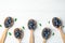 Flat lay composition of spoons with tasty blueberries and leaves on white wooden table