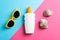Flat lay composition with sunglasses, sunscreen pray and seashell on two tone background, top view, closeup