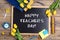 Flat lay composition for Teacher`s day on chalkboard with school supplies and tulip flowers on a rustic wooden table