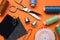 Flat lay composition with thimbles and different sewing tools on orange background