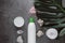 Flat lay composition with white cosmetic products, candle and green leaf on gray concrete background.