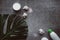 Flat lay composition with white cosmetic products, candle and green leaf on gray concrete background.