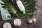 Flat lay composition with white cosmetic products, candle, towel and green leaf on gray concrete background.