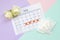 Flat lay composition with white roses and menstrual tampons and pad packs on menstruation period calendar and blue pink and lilac